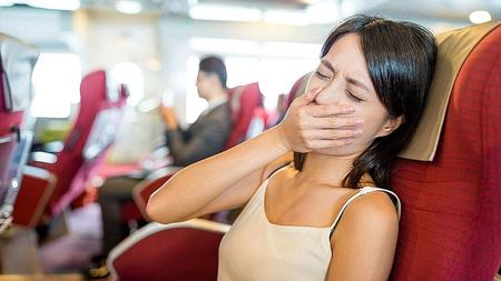Reiseübelkeit: Frau fühlt sich übel im Flugzeug