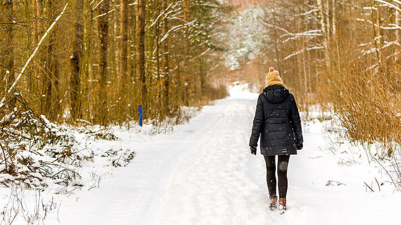 Depressive Frau geht im Winter im Wald spazieren