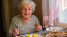 Ältere Frau mit Mangelernährung isst gesundes Essen zu Mittag.