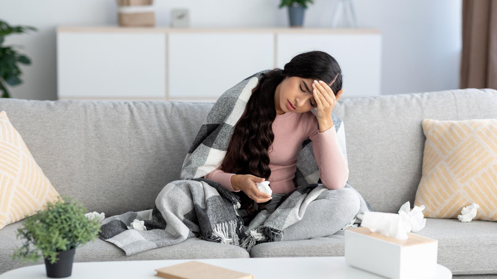 Frau liegt mit Fieber auf der Couch