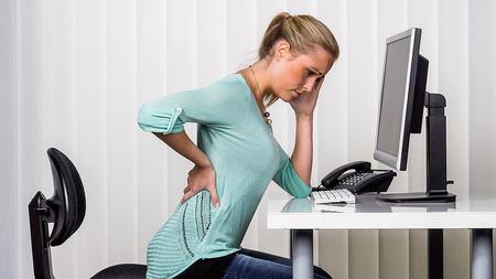 Frau hat Schmerzen im Rücken - ein möglicher Bandscheibenvorfall