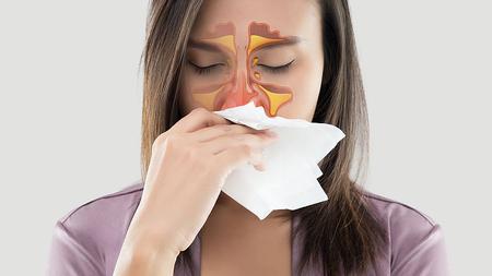 Frau mit Sinusitis schnäuzt sich die Nase