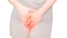 Frau hat wegen bakterieller Vaginose Schmerzen im Unterleib und hält sich den Intimbereich