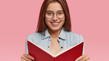Mädchen mit Brille liest ein Buch. 