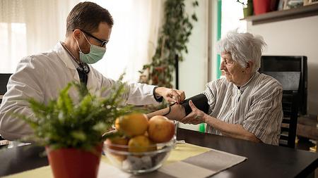 Ältere Frau mit Bluthochdruck bekommt vom Arzt eine Blutdruckmesssung.