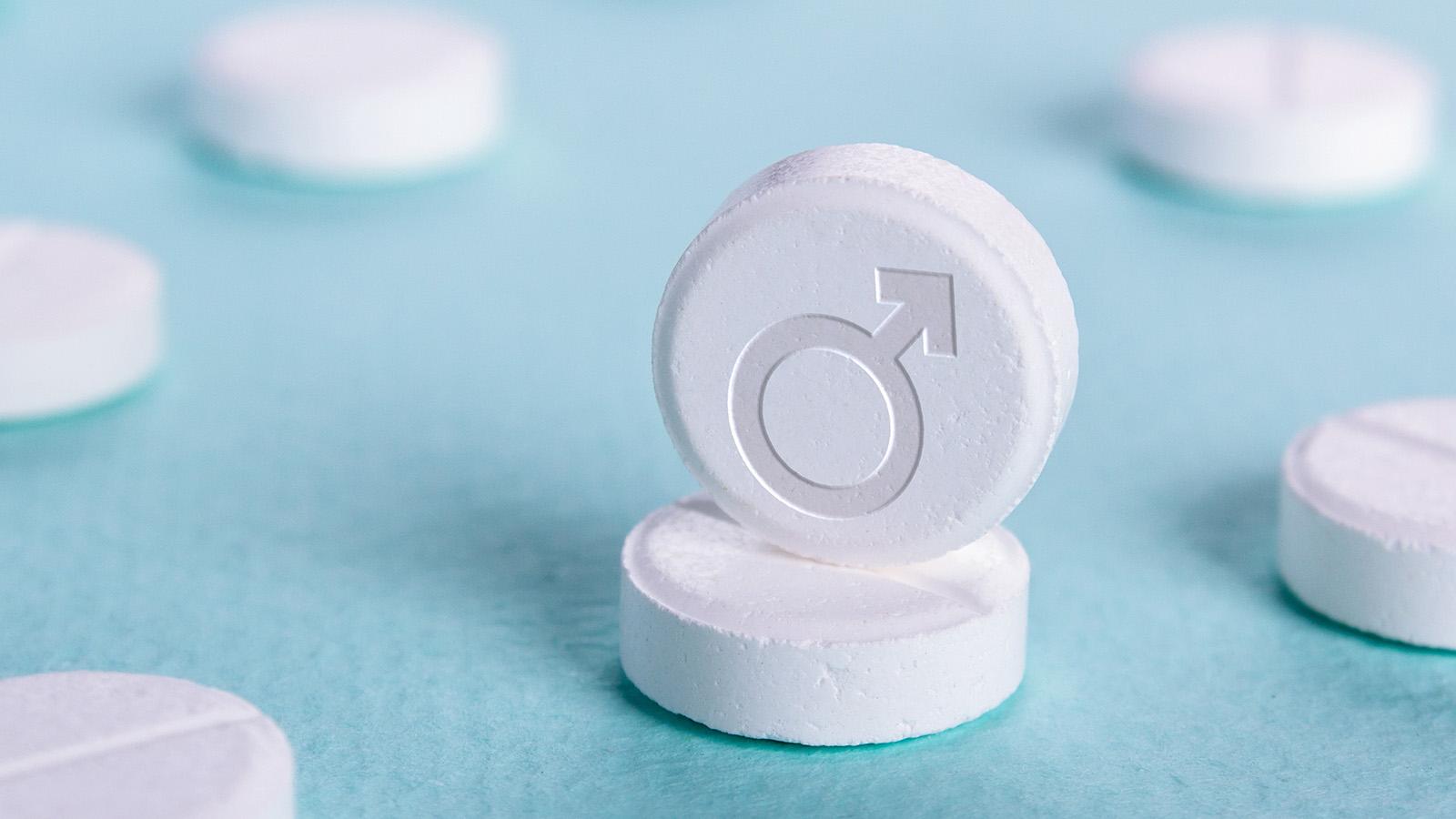 auf blauem Untergrund liegen mehrere Pillen, gekennzeichnet mit Symbol für männliches Geschlecht