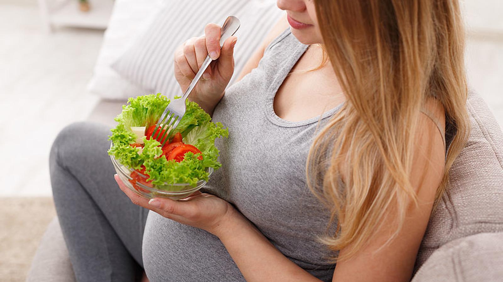 Schwangere Frau isst einen Salat