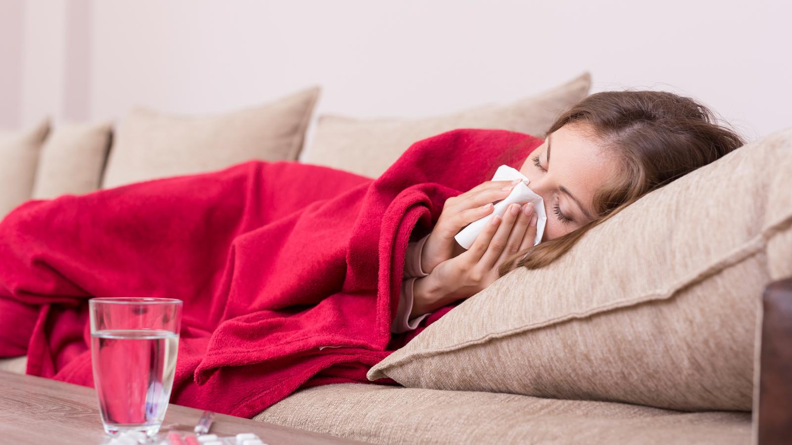 Frau mit Influenza liegt krank im Bett