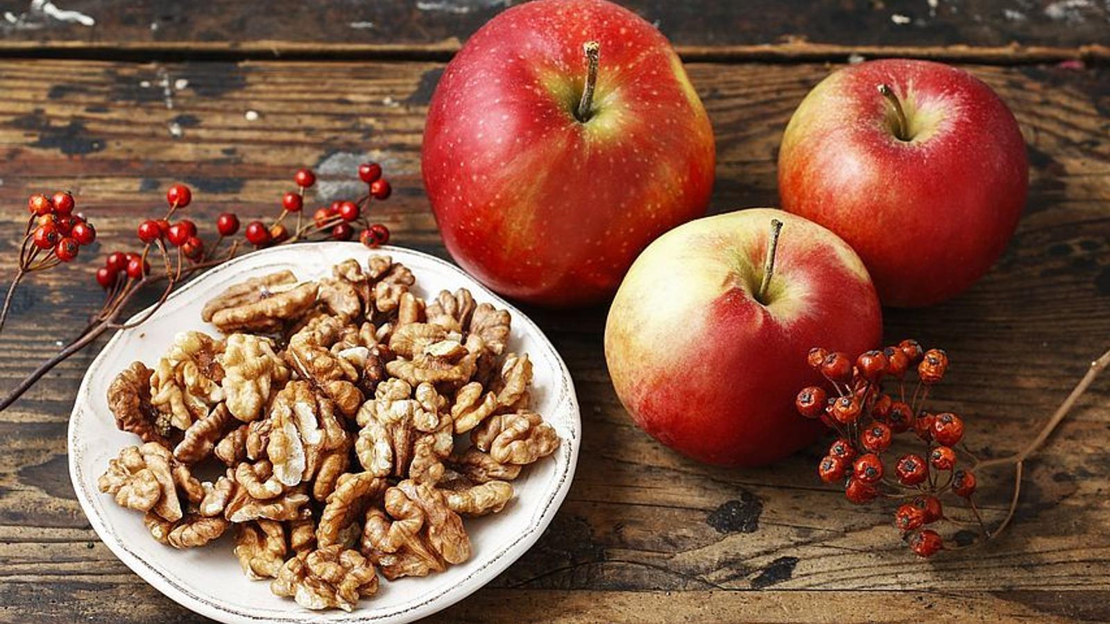 ein Schüssel mit Nüssen und Äpfel auf einem Holztisch