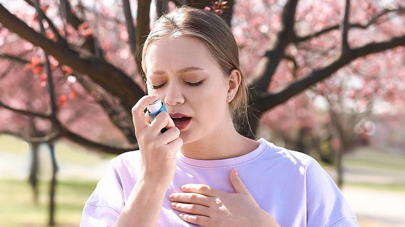 Frau verwendet Inhalator, weil sie Asthma hat, das durch eine Erkältung ausgelöst wurde