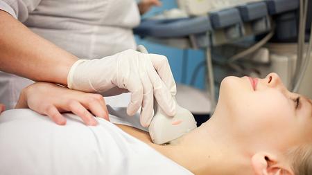 Arzt führt Ultraschall der Schilddrüse bei einer Patientin durch.
