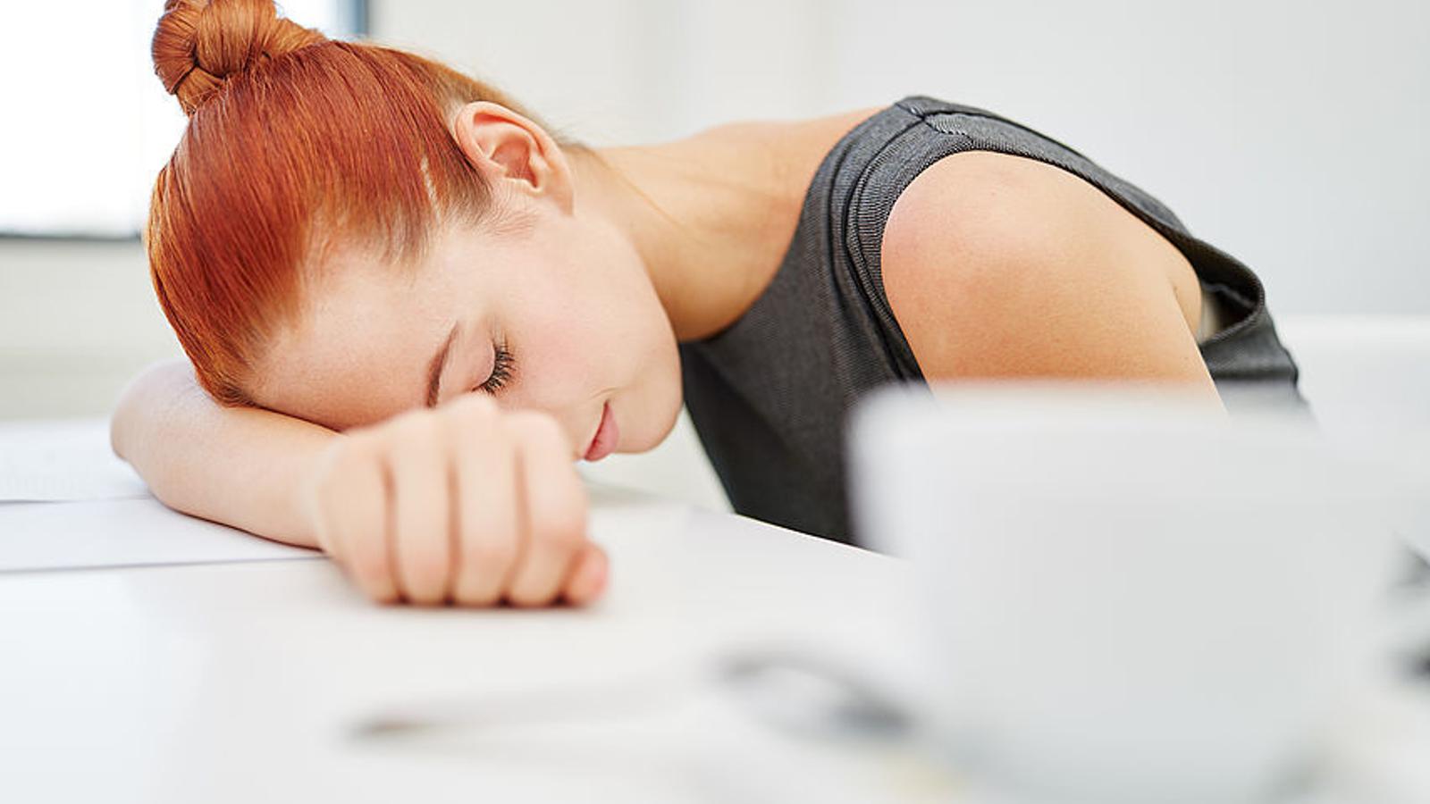 Frau legt erschöpft den Kopf auf den Tisch. 