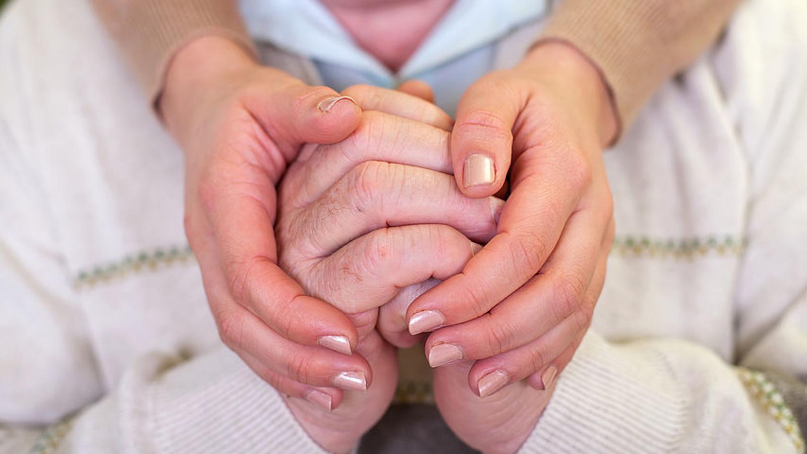 Frau hält die Hände ihres demenzkranken Mannes