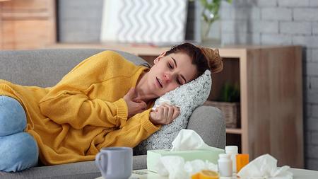 Frau liegt mit Erkältung am Sofa