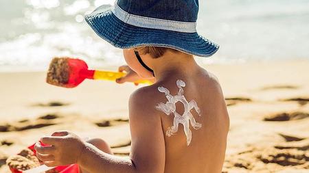 Sonnencreme auf einem Kind das am Strand spielt