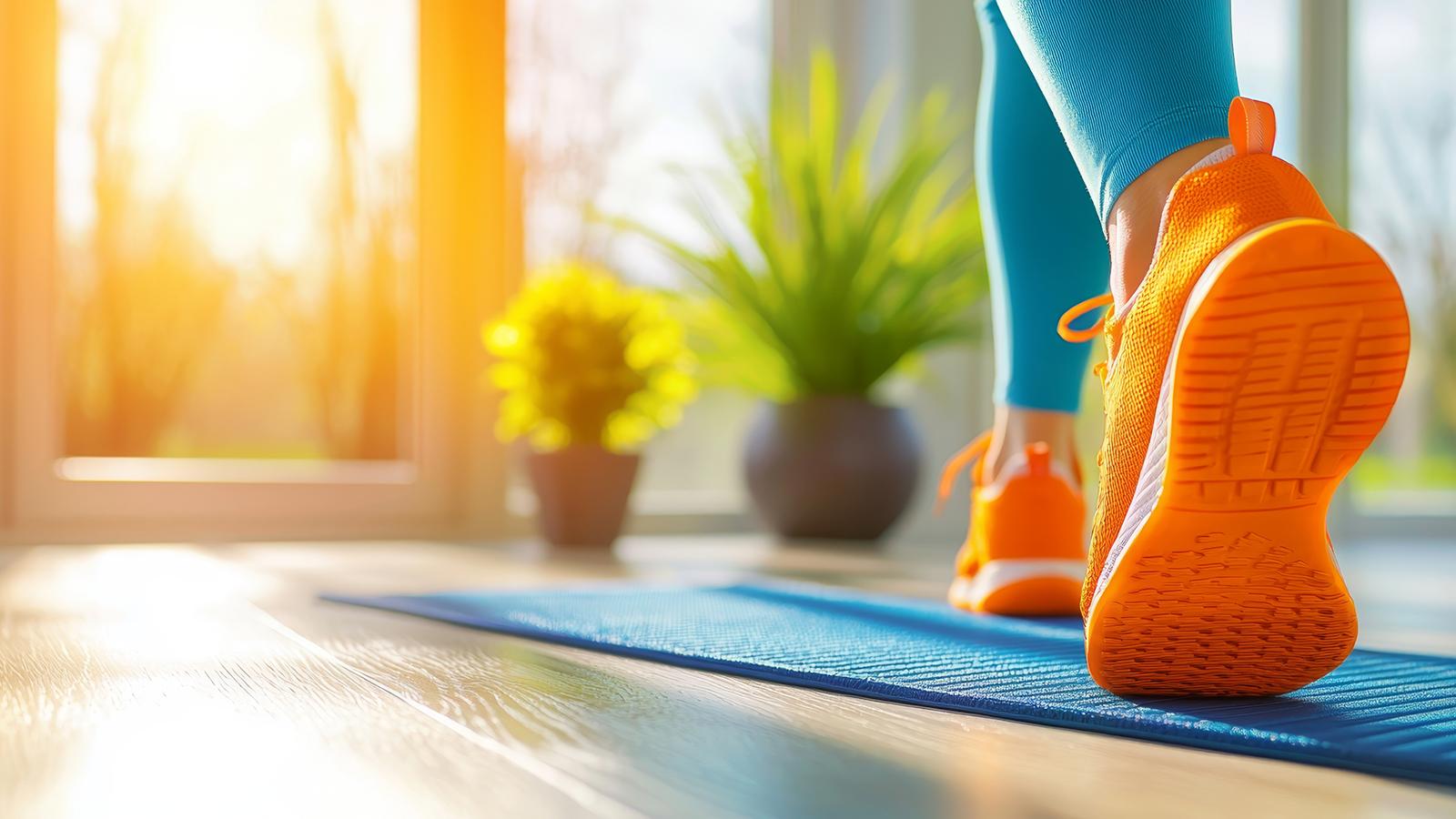 Beine einer Frau in Sportschuhen auf einer Fitnessmatte, Bewegung am Morgen