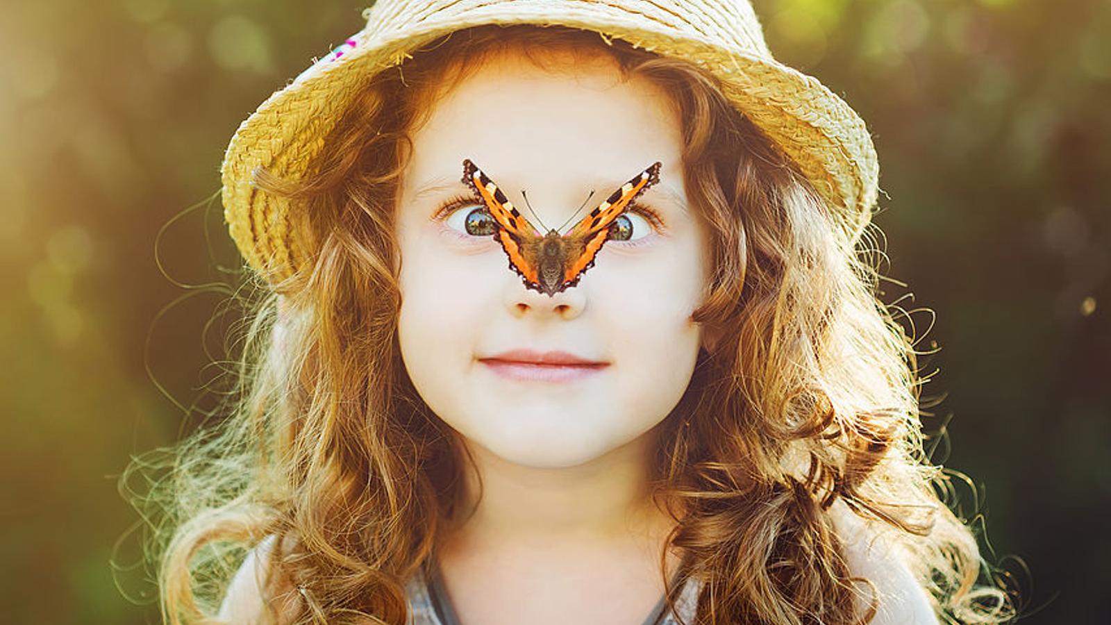 Mädchen hat einen Schmetterling auf der Nase sitzen. 
