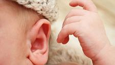 Schwerhöriges Baby greift Richtung Ohr