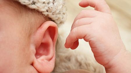 Schwerhöriges Baby greift Richtung Ohr