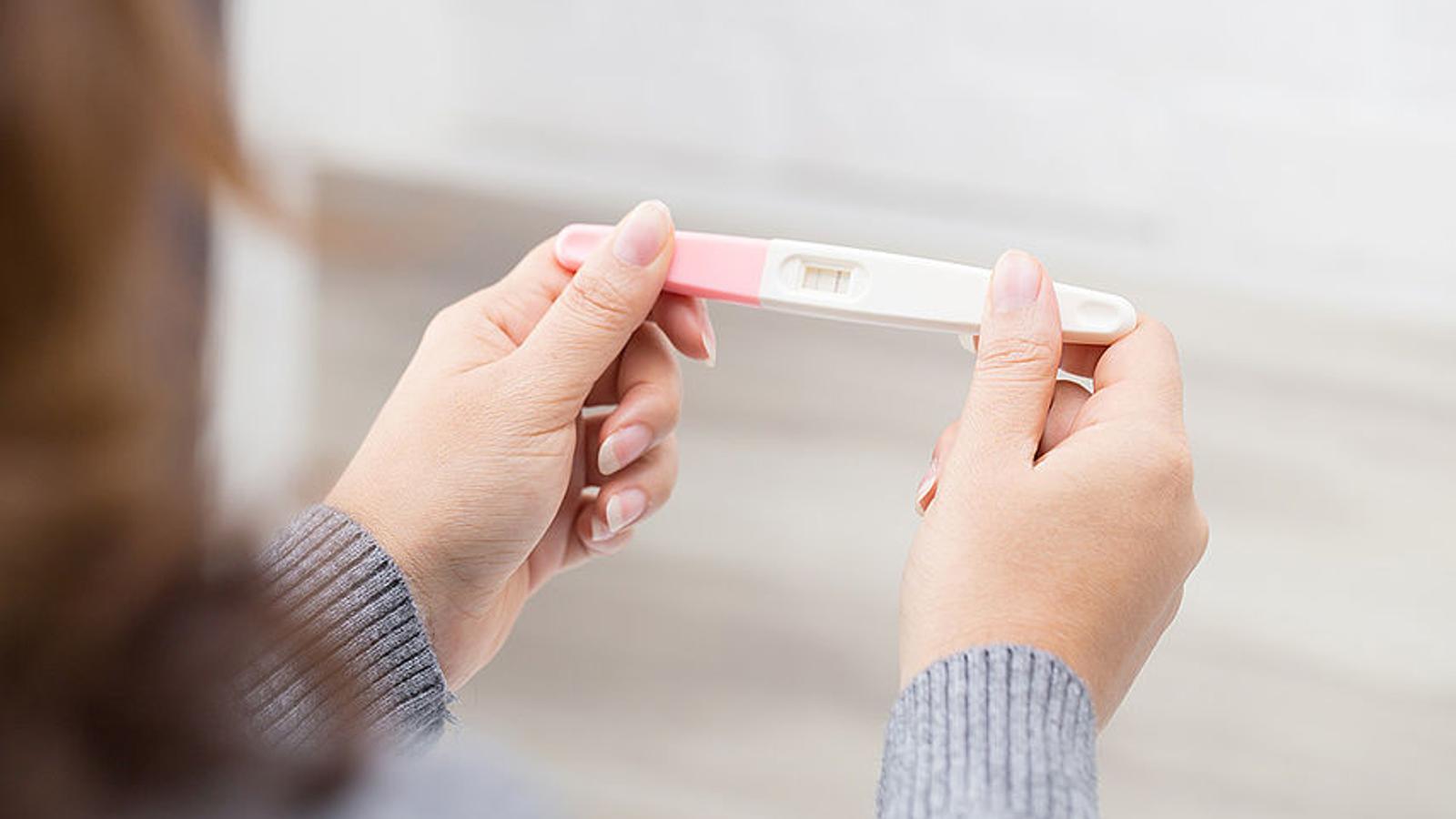 Frau hält Schwangerschaftstest in den Händen