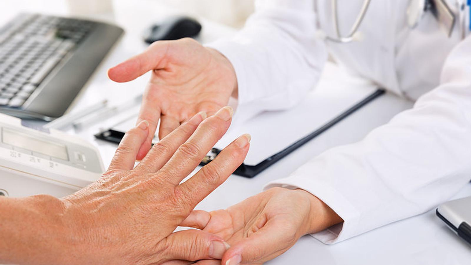 Doktor schaut sich die schmerzende Hand eines Patienten an