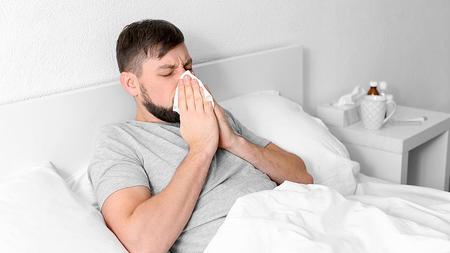 Mann liegt mit Grippe im Bett