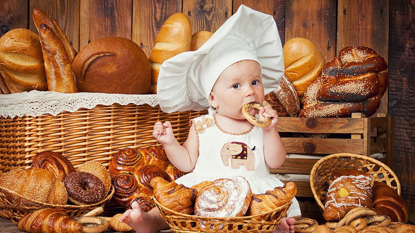 Baby sitzt umringt von Gebäck und ist eine Bretzel