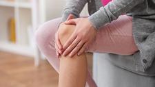 Frau mit Gelenkschmerzen hält sich ihr Knie
