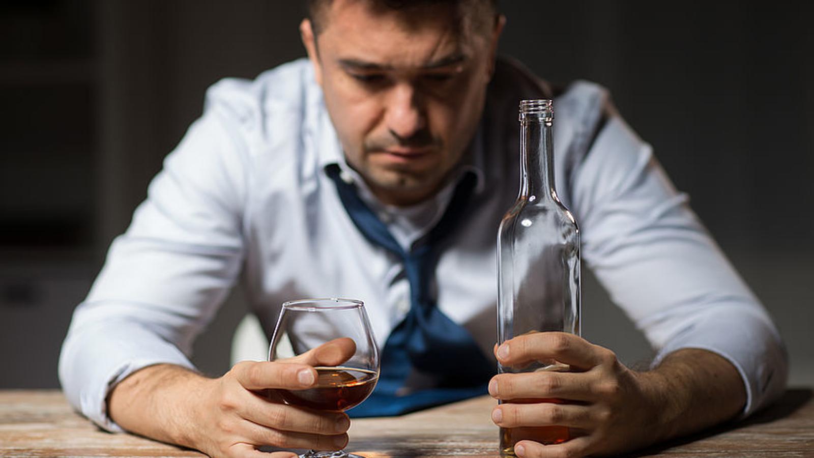 Mann mit Alkoholproblem sitzt vor einem Glas Wein