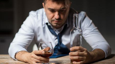 Mann mit Alkoholproblem sitzt vor einem Glas Wein