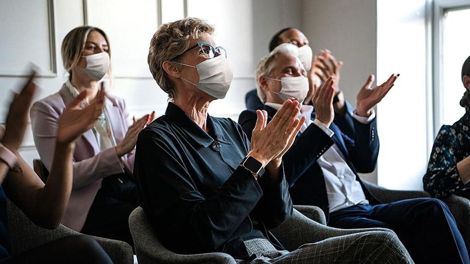Teilnehmer sitzen bei einem Vortrag mit Schutzmaske.