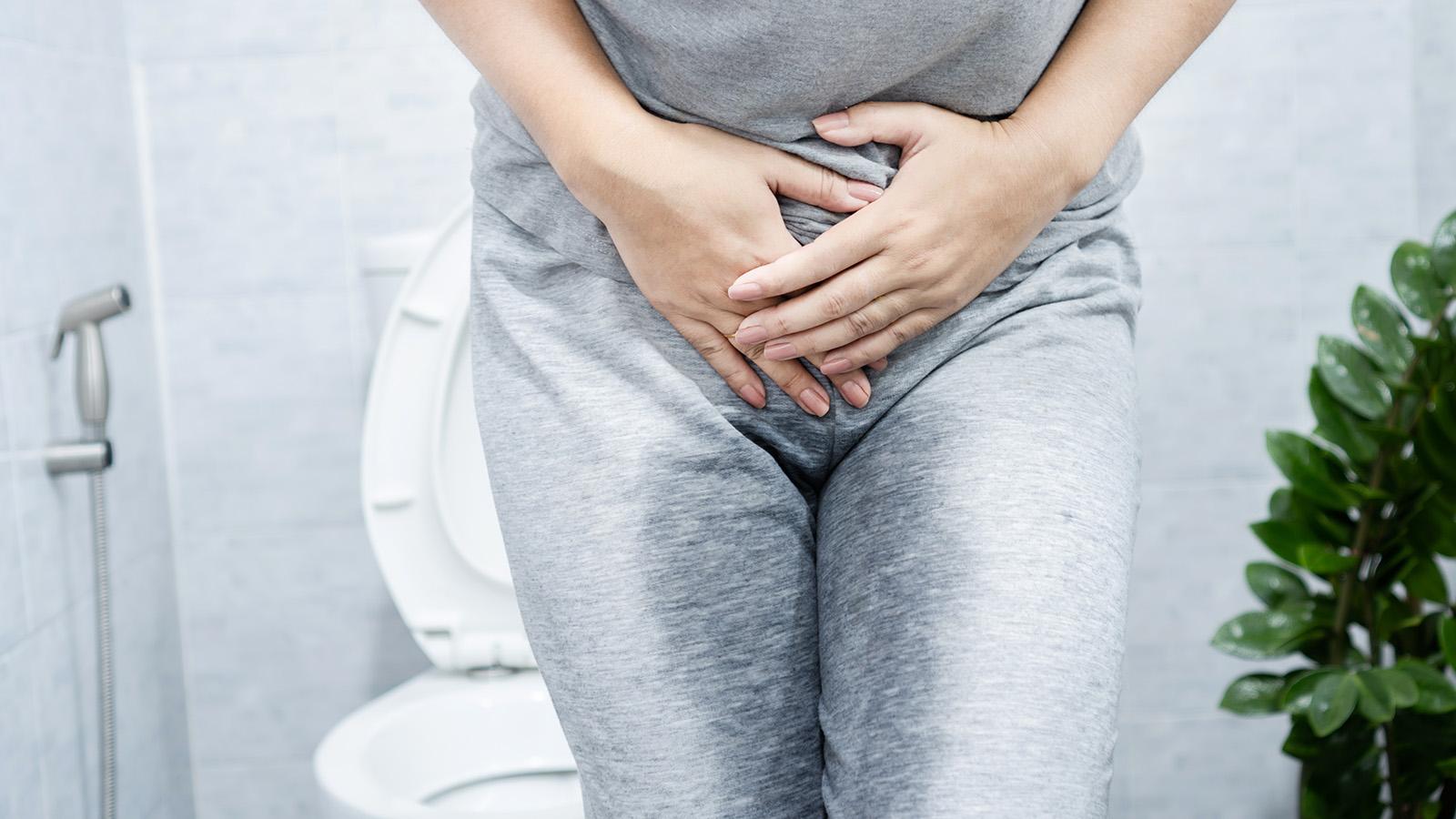 Frau steht mit nasser Hose im Badezimmer