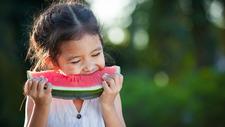 Mädchen beißt von Wassermelone ab 