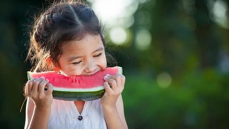 Mädchen beißt von Wassermelone ab 