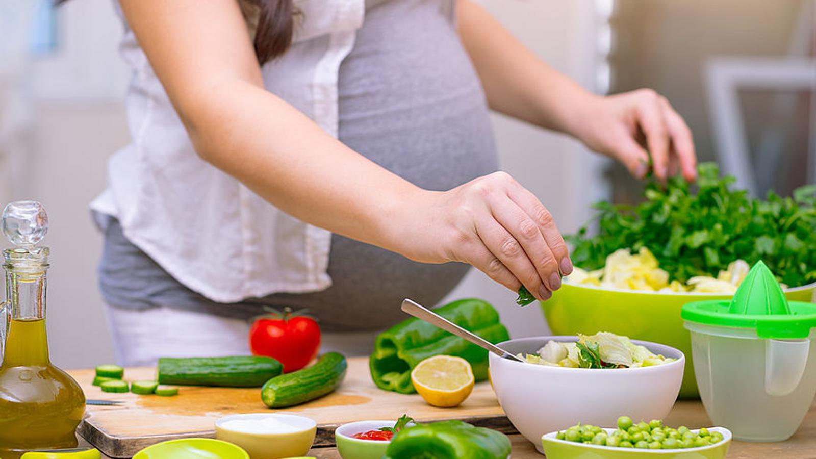 Schwangere Frau bereitet einen Salat vor. 