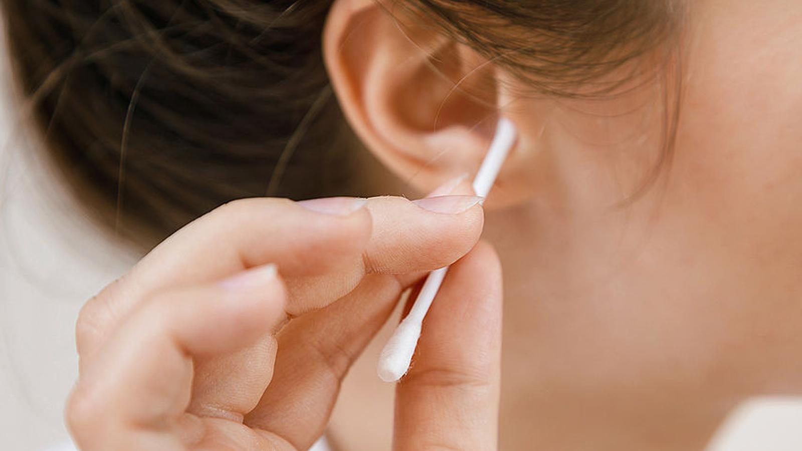 Frau reinigt sich das Ohr mit einem Wattestäbchen