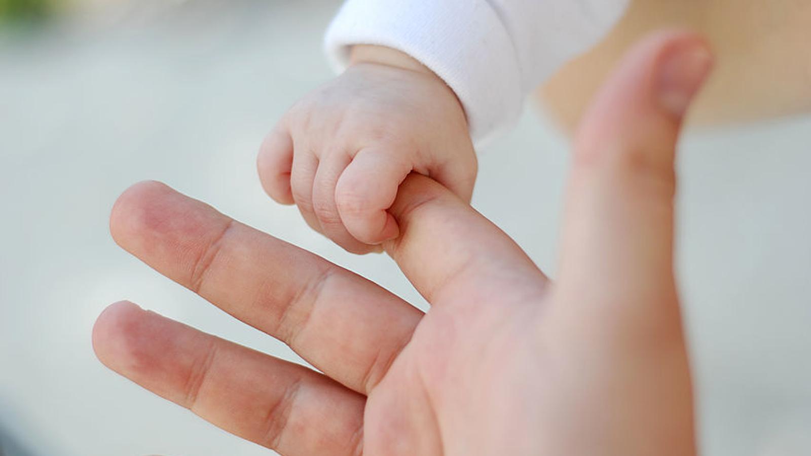 Baby greift nach der Hand von Mama oder Papa