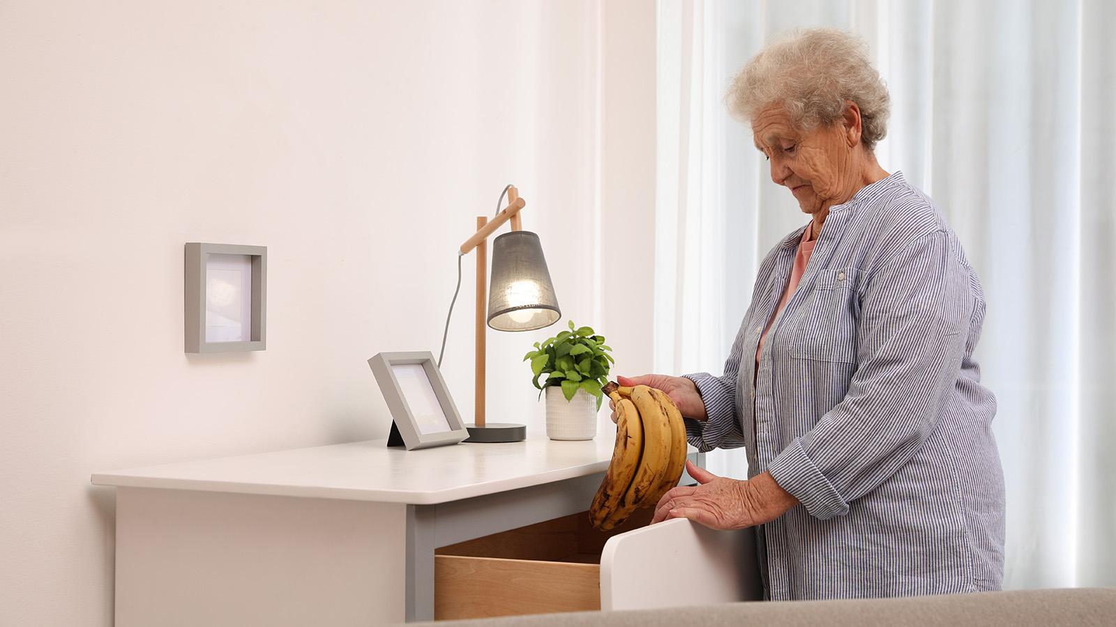 Alte Frau mit Demenz gibt Bananen in die Kommode