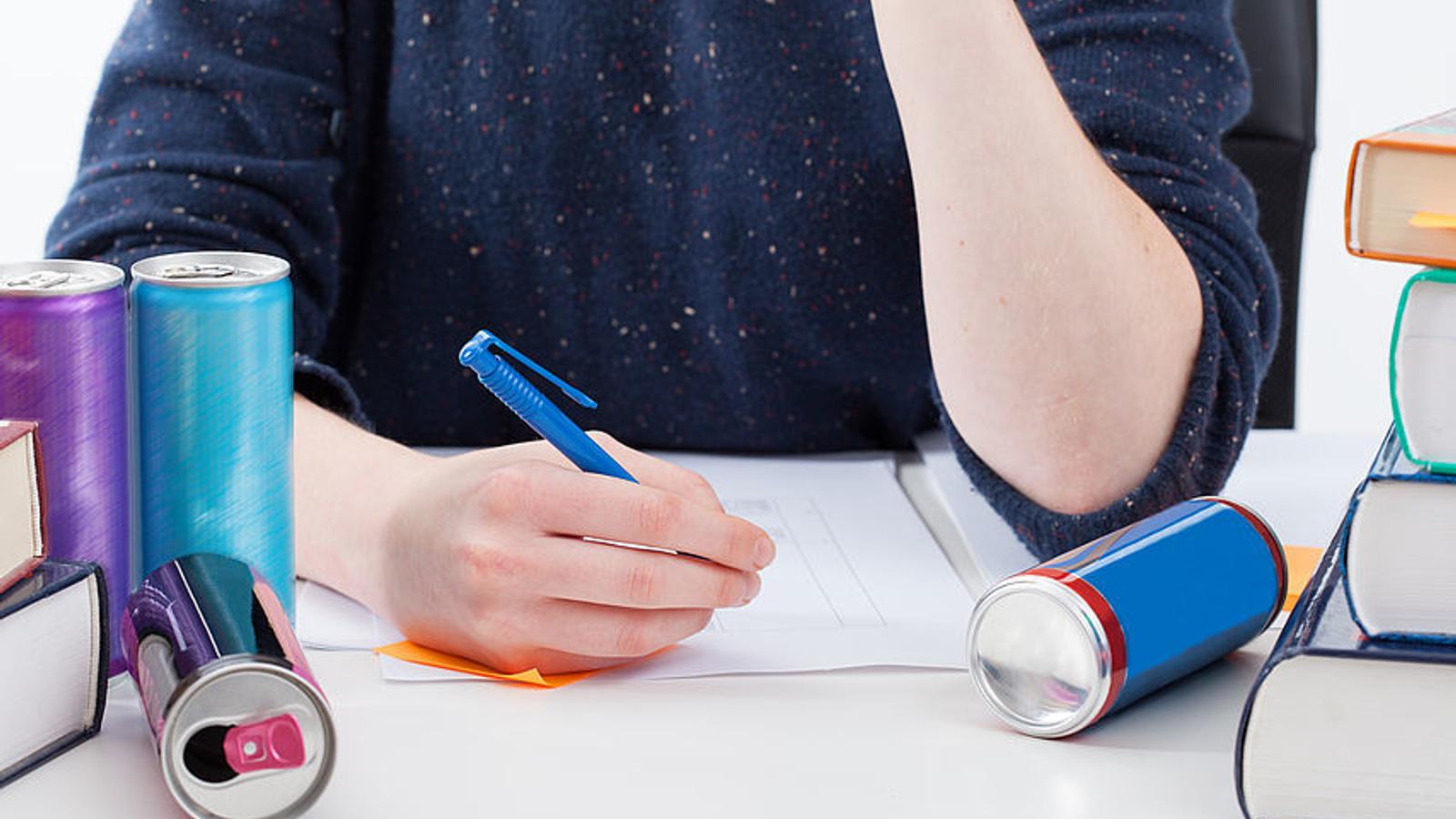 Schüler schreibt Hausaufgaben und trinkt Energy Drinks