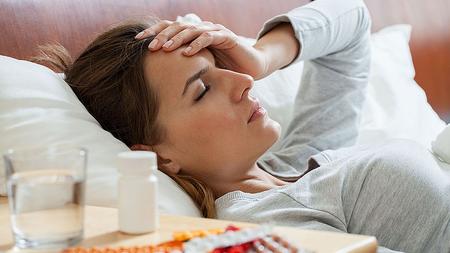 Frau mit Influenza liegt krank im Bett