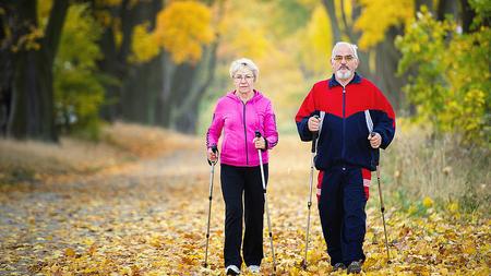 Älteres Ehepaar geht Nordic Walken, um Arthrose zu mildern.
