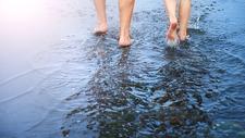 Kneipp-Medizin: Zwei Menschen gehen barfuß durchs Wasser