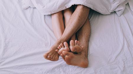 Füße eines verliebten Paares im Bett, nachdem sie während der Regel Sex hatten