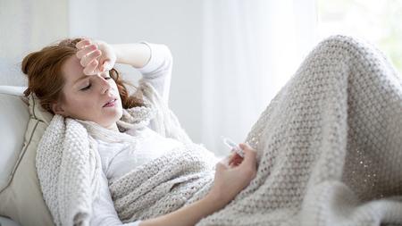 Frau mit Eierstockentzündung liegt mit Fieber im Bett