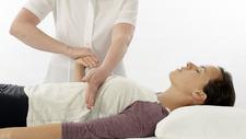 Frau mit Schmerzen wird mittels Angewandter Kinesiologie behandelt.