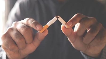 Mann zerbricht Zigarette als Symbol für den Rauchstopp