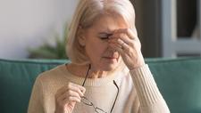 Ältere Frau greift sich wegen Kopfschmerzen an die Stirn
