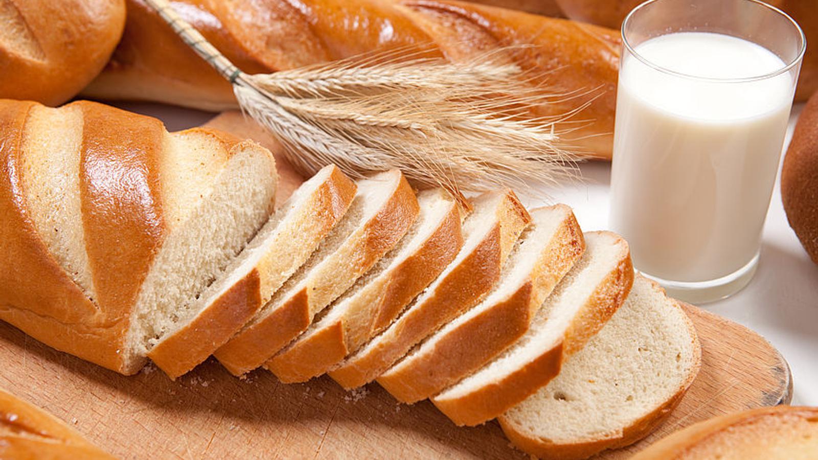 Ein großes Stück Weißbrot und ein Glas Milch auf einem Tisch