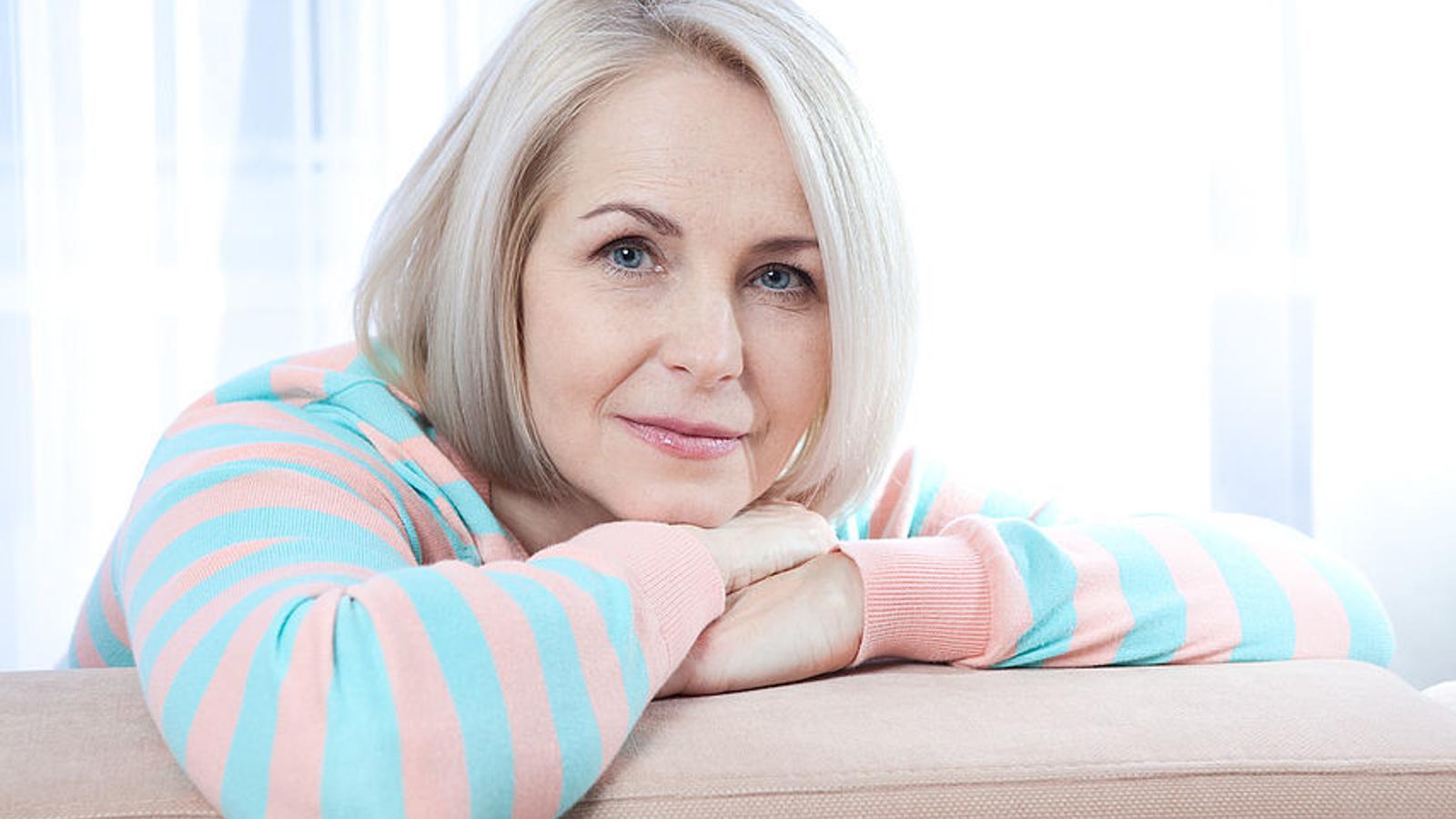 Frau in den Wechseljahren lehnt am Sofa