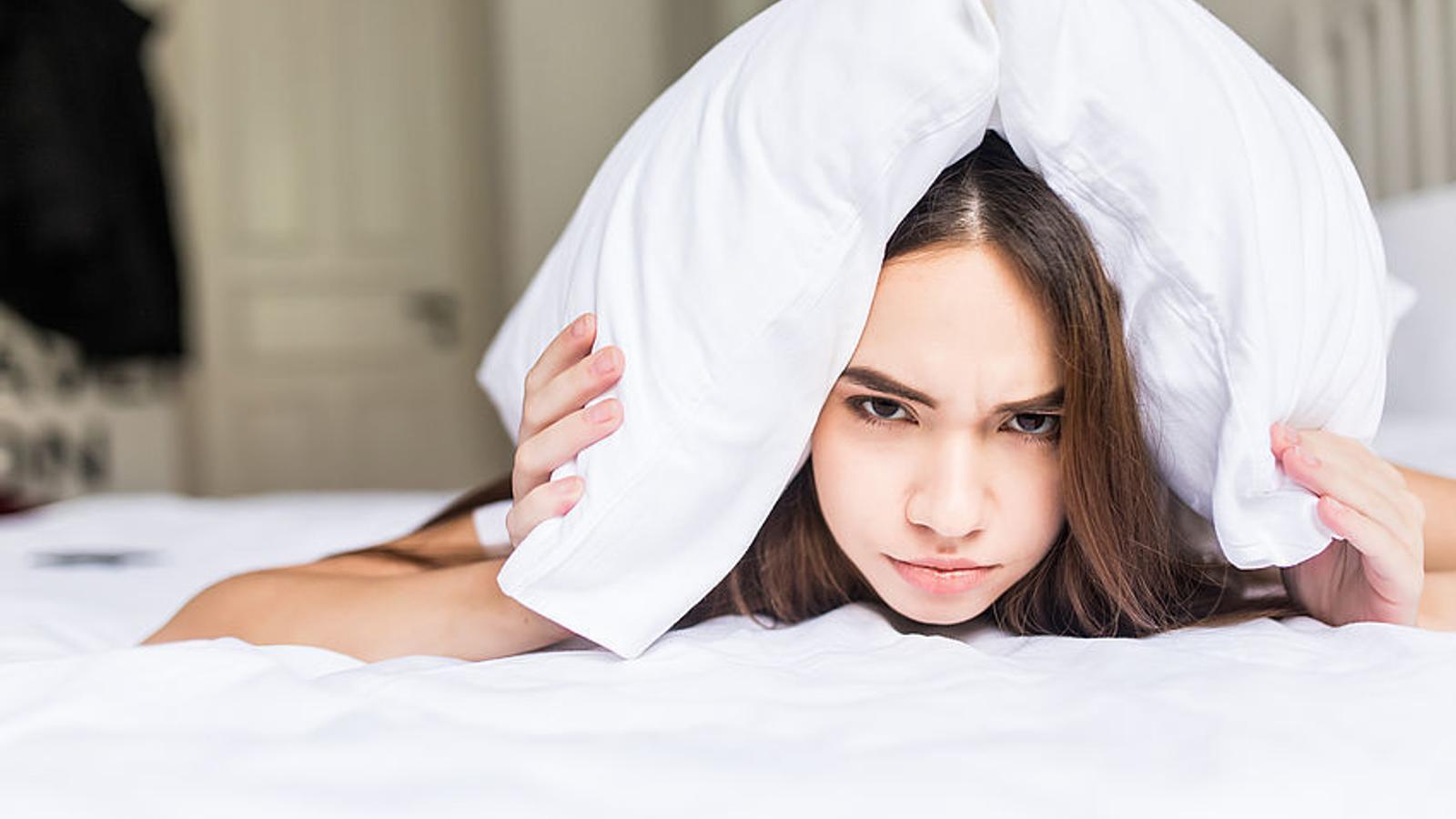 Frau mit Sex-Schmerzen liegt frustriert im Bett
